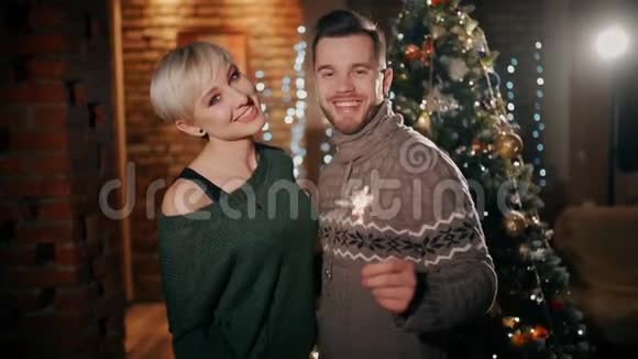 圣诞节时一对年轻夫妇正高兴地互相亲吻手里拿着火花新年快乐视频的预览图