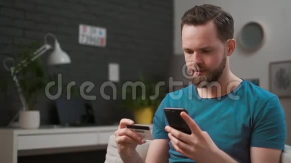 男人在家里用智能手机用信用卡付款高加索人用智能手机网上购物容易通过视频的预览图