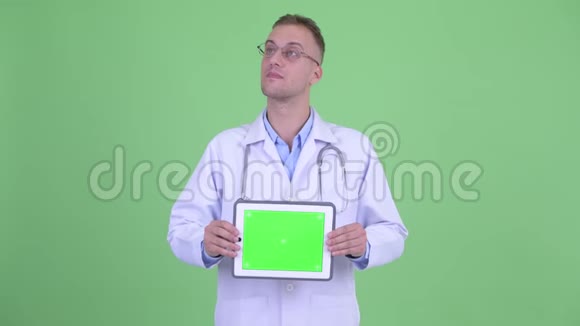 快乐的帅哥医生在看数字平板电脑视频的预览图