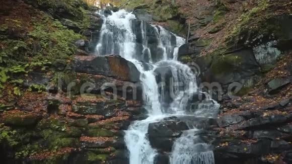 山瀑布落在灰色大岩石附近有苔藓视频的预览图