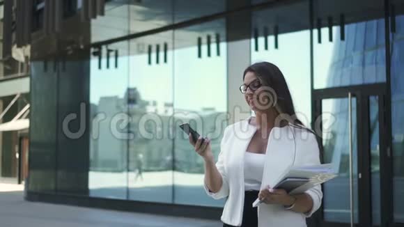 年轻成功的律师正在看智能手机屏幕在现代建筑背景下摆姿势视频的预览图