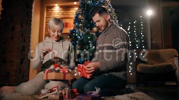 一对年轻夫妇正在打开圣诞礼物一起解开圣诞礼物视频的预览图