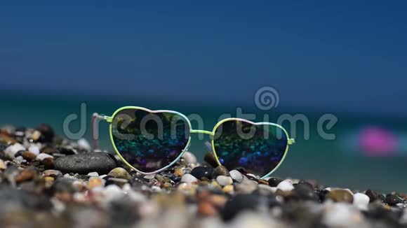 太阳镜躺在沙子上戴着墨镜反射着大海海浪和天空视频的预览图