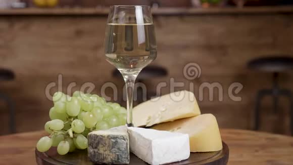 在一个圆形的木制托盘上用各种奶酪旋转一杯葡萄酒视频的预览图