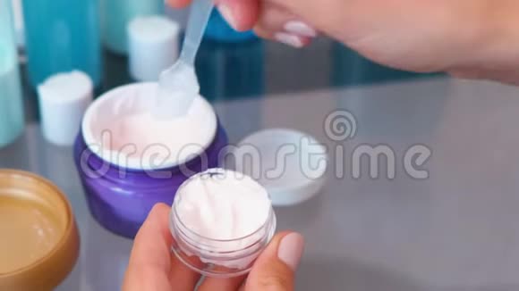 女人手把一个大罐子里的奶油放进一个小罐子里里面有一个铲子道套的化妆品特写罐子顶级视频的预览图