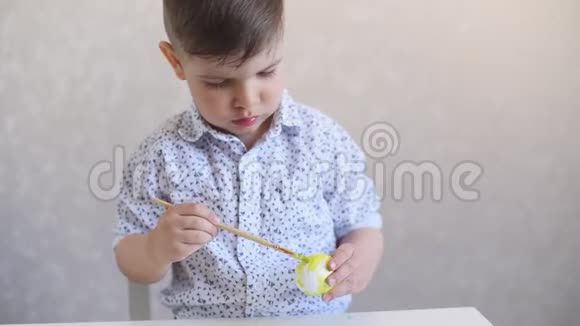 一个小孩在桌子上画一个白色背景的复活节彩蛋视频的预览图