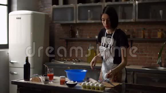 一个女人把鸡蛋放进厨房的碗里视频的预览图