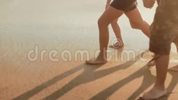 白种人一家人赤脚在海滩和海浪上行走的腿视频的预览图