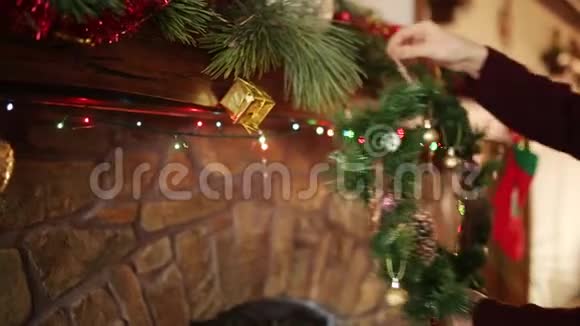 戴着针织毛衣和帽子的人在壁炉上方挂着圣诞袜袜子和花环上面装饰着五颜六色视频的预览图