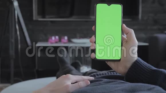 绿色屏幕一个男人在客厅里看着一部智能手机然后刷卡视频的预览图