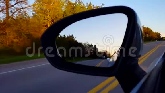 日落时驾驶乡村道路侧镜司机视角POV向下看侧视镜沿街道近黄昏视频的预览图
