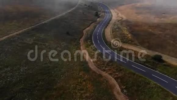 从空中俯瞰群山之间的空路有很多云雾的道路视频的预览图