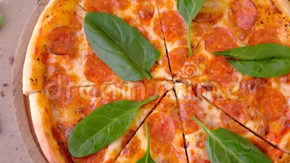意大利腊肠披萨切片木板上有菠菜叶特写顶景视频的预览图