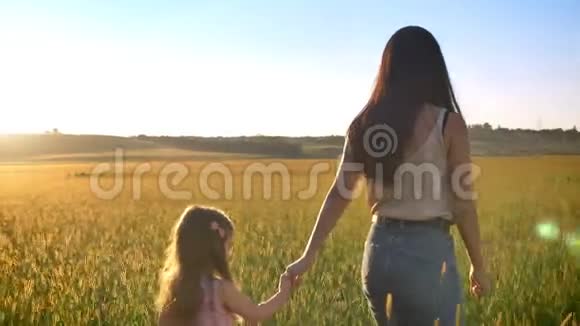 母亲带着孩子的剪影在夏天的田野里散步家庭观念侧视视频的预览图