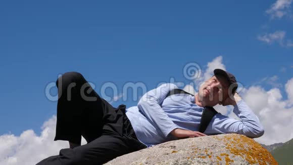 旅行者躺在大石头上休息在山上旅行蓝天背景视频的预览图