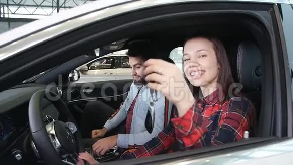 一对年轻幸福的夫妇买了一辆新车微笑并显示钥匙视频的预览图