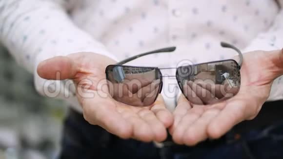特写男人手拿着墨镜眼镜那个人穿着一件白色衬衫保健概念视频的预览图