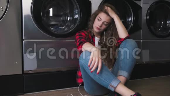 年轻漂亮的女人红色的卷发穿着红色的酒石衬衫在洗衣房里感到沮丧慢动作视频的预览图