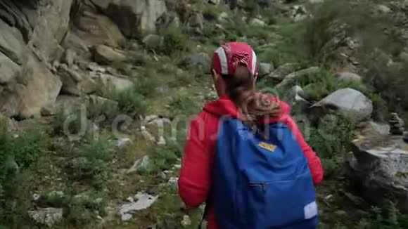 旅行者女孩戴着帽子背着背包爬山背面视频的预览图