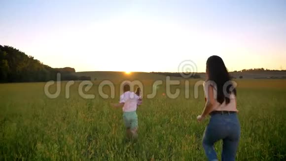 母亲带着孩子的剪影在夏天的田野里奔跑家庭观念视频的预览图