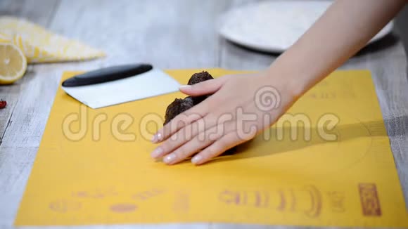 女人的手捏着巧克力面团在一张白色的桌子上做新年饼干烹饪课的概念视频的预览图