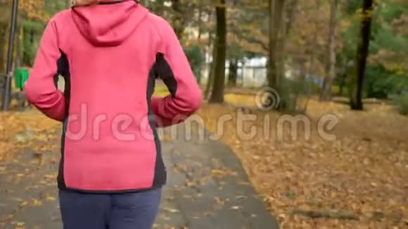 运动的小女孩雨后在秋天的公园里跑步后视图视频的预览图