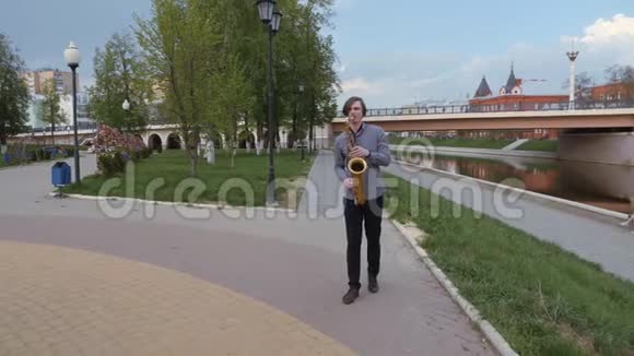 年轻人演奏萨克斯管城市背景上的人他的风景吹进了管道里音乐家去了视频的预览图