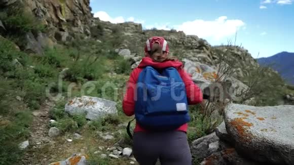 年轻的旅游妇女戴着帽子背着背包爬山背面视频的预览图
