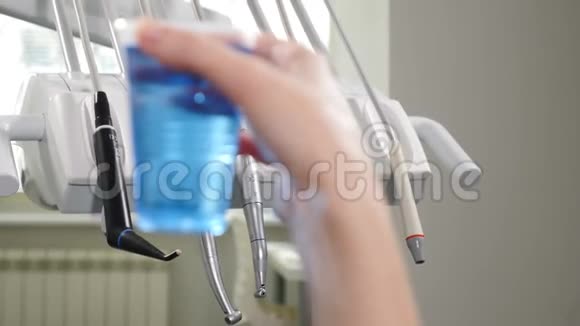 现代牙科诊所医疗设备在不聚焦与塑料杯与蓝色无菌液体在前面4k视频的预览图