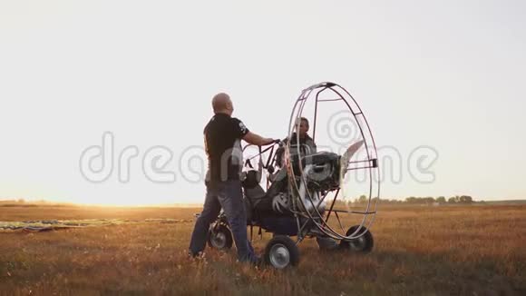 汽车滑翔伞在日落时分用一个木制螺旋桨站在田野里两名飞行员对发动机进行了一次试车视频的预览图