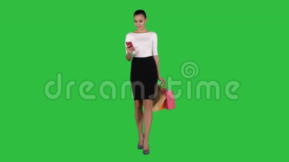 快乐的年轻女人带着智能手机在白色背景上拍摄她的购物袋视频的预览图