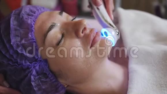 美容师带有微磨擦装置为躺在水疗中心的年轻妇女做面部去角质视频的预览图
