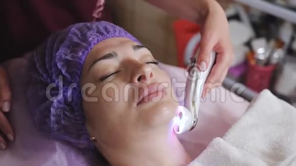 美容技术概念美容师与微磨擦装置做面部去角质年轻妇女视频的预览图