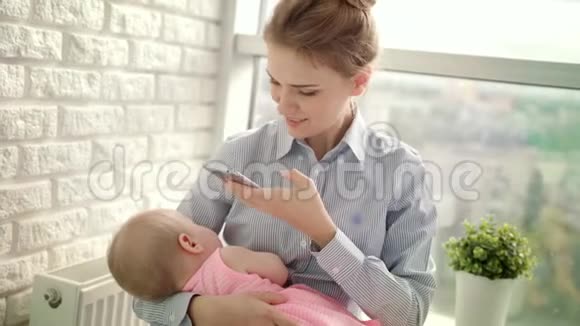 穿衬衫的漂亮女人拍女孩的手机照片妈妈给宝宝拍照视频的预览图