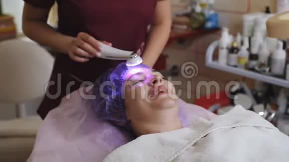 美容技术概念美容师与微磨擦装置做面部去角质年轻妇女视频的预览图