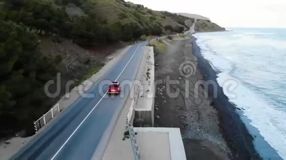 红色复古车行驶在靠近大海的路上空中影院视频的预览图