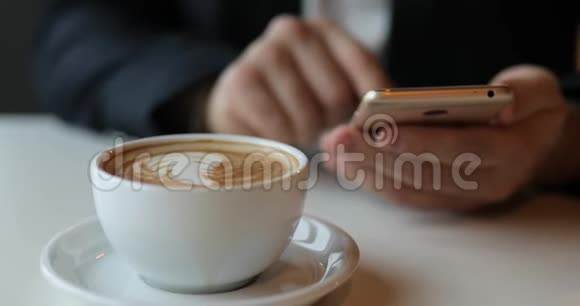 在咖啡馆里使用智能手机的商人前台提供拿铁视频的预览图