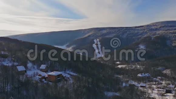 冬季山区的乡村景观雪覆盖的房子在村庄的雪从一个高度从空中飞过视频的预览图