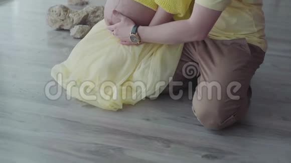 有爱心的丈夫轻轻地拥抱他怀孕的妻子孕妇的手和腹部特写慢动作视频的预览图