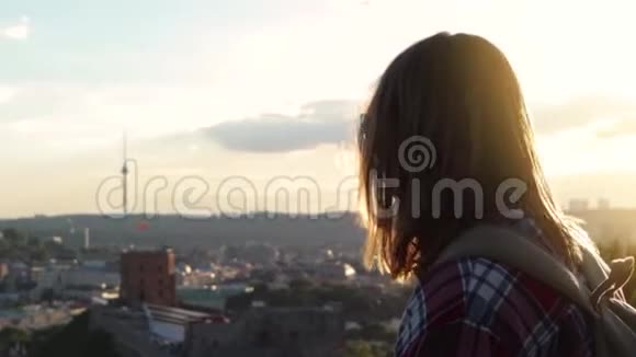 一个年轻的女人站在夕阳的背景下视频的预览图