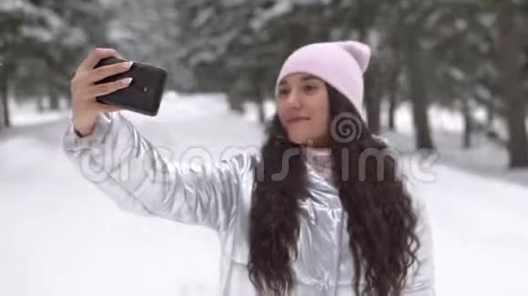 一个女孩用智能手机在冬季森林4K自拍视频的预览图