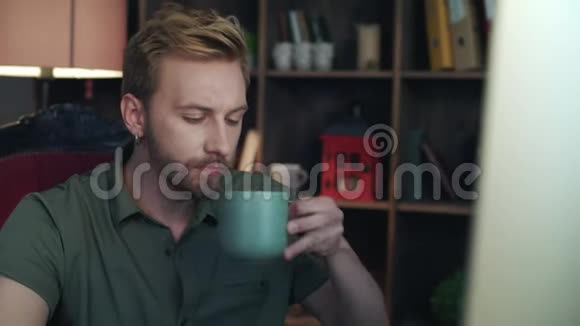 创意设计师在创业办公室喝茶看电脑屏幕的人视频的预览图