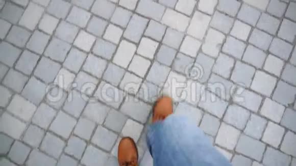 穿着牛仔裤和棕色靴子的时髦旅行者在铺路板上行走上景视频的预览图