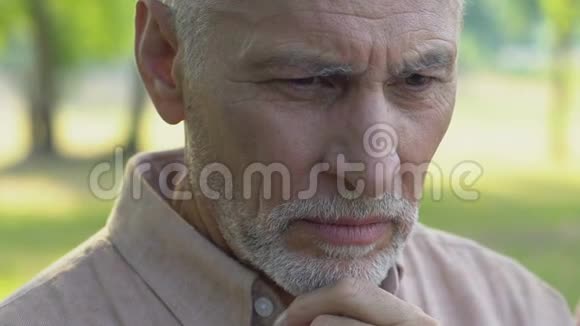 孤独的老人坐在公园里痛苦地哭泣双手紧闭着脸视频的预览图