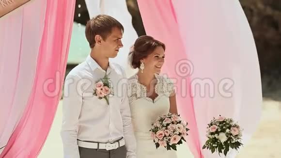 新娘和新郎在花拱的背景下在菲律宾海滩举行婚礼视频的预览图