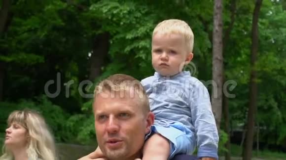 小可爱的男孩坐在爸爸脖子上公园爸爸天视频的预览图