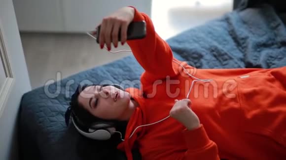 年轻女孩通过智能手机聊天在线视频聊天躺在家里的床上视频的预览图