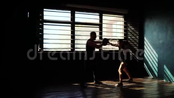 适合的白人女拳击手训练剪影与拳击教练在健身房视频的预览图