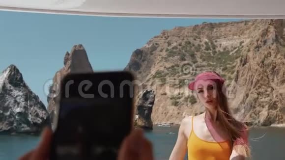 有人在电话里拍了一张照片照片是一个穿泳衣的漂亮女孩在海湾里的游艇上慢动作的岩石视频的预览图