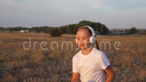 年轻的运动女孩戴着耳机慢跑一个年轻女孩在日落时训练听音乐视频的预览图